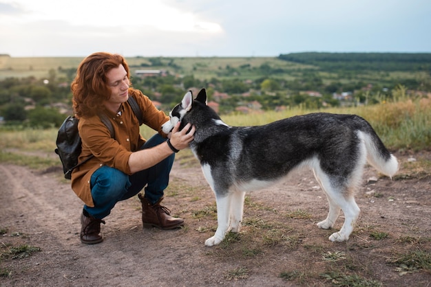 Foto gratuita hombre sonriente de tiro completo acariciar a un perro