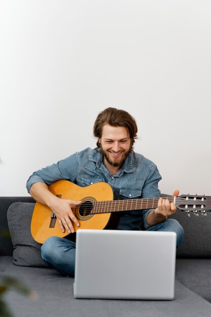 Hombre sonriente de tiro completo con guitarra