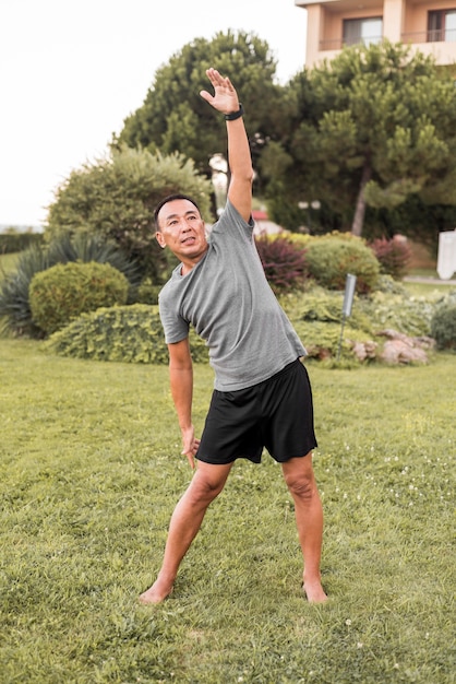 Hombre sonriente de tiro completo haciendo ejercicio en la naturaleza