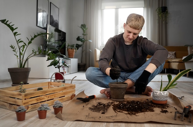 Foto gratuita hombre sonriente de tiro completo jardinería en casa