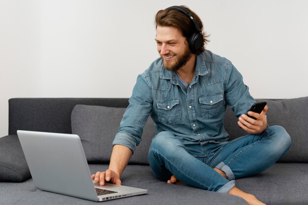 Hombre sonriente de tiro completo con laptop