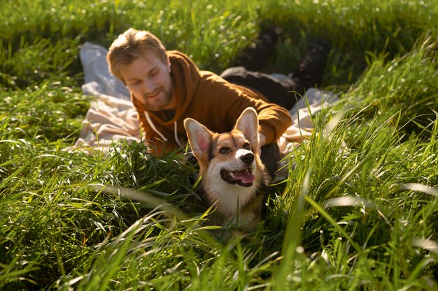 Hombre sonriente de tiro completo con perro en la naturaleza