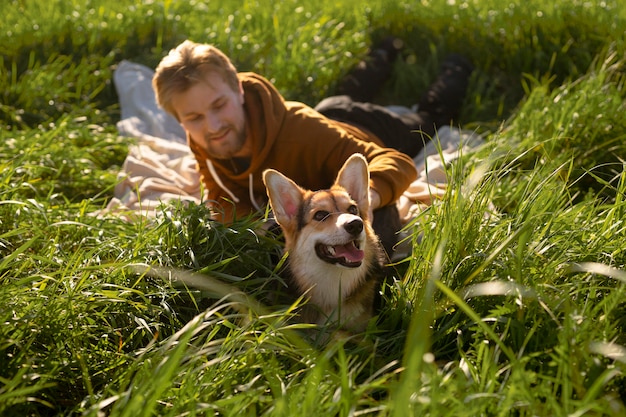 Hombre sonriente de tiro completo con perro en la naturaleza