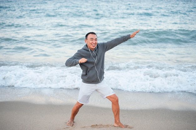 Hombre sonriente de tiro completo en la playa