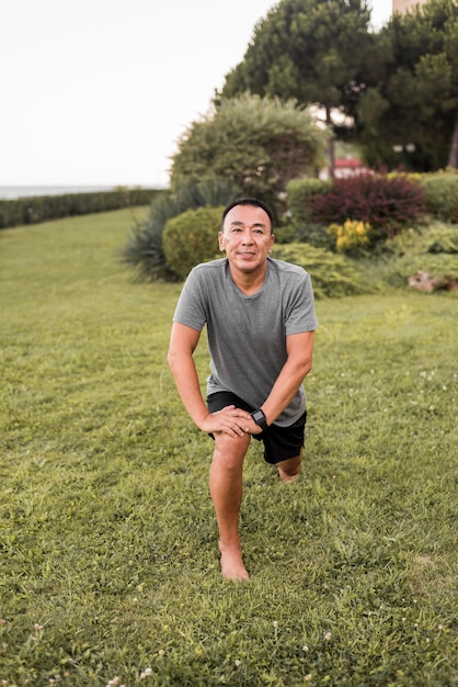 Hombre sonriente de tiro completo que se extiende en la naturaleza