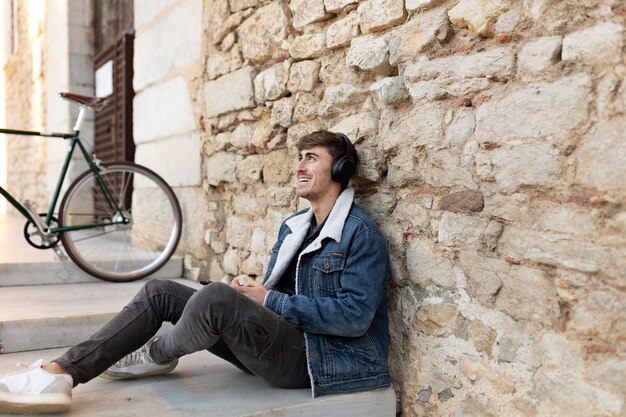 Hombre sonriente de tiro completo sentado al aire libre