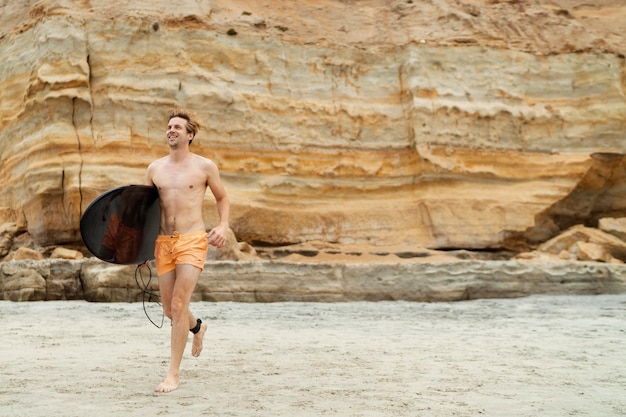 Hombre sonriente de tiro completo con tabla de surf