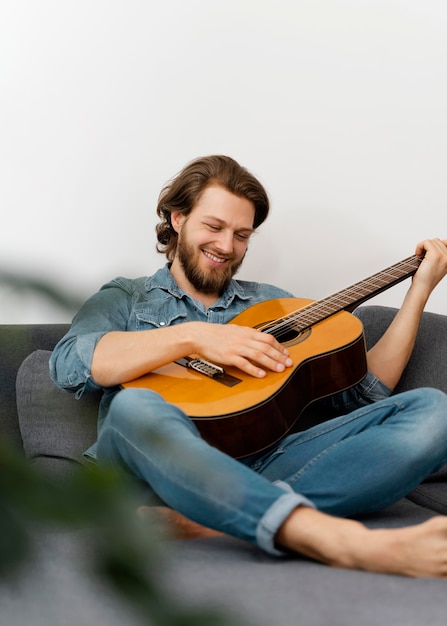 Hombre sonriente de tiro completo tocando la guitarra