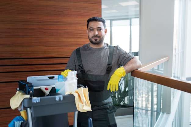 Hombre sonriente de tiro medio con carrito de limpieza