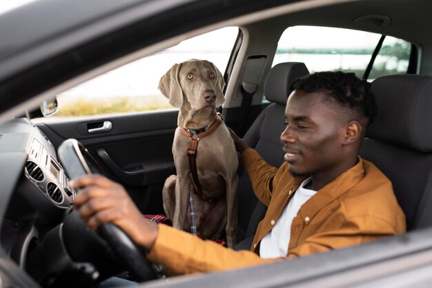 Hombre sonriente de tiro medio conduciendo con perro