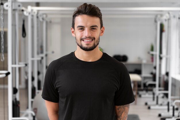 Hombre sonriente de tiro medio en el gimnasio