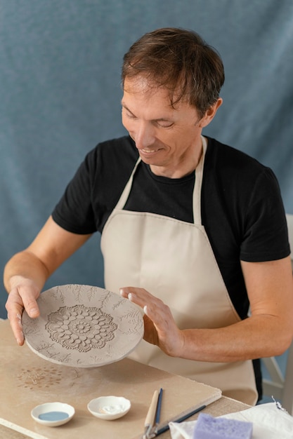 Hombre sonriente de tiro medio haciendo cerámica