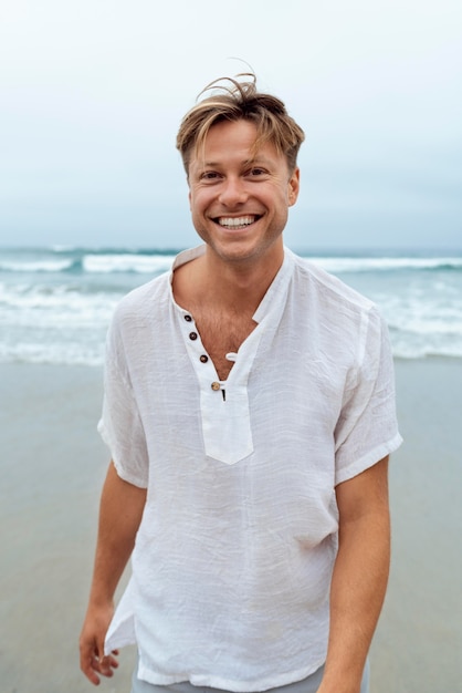 Hombre sonriente de tiro medio en la playa