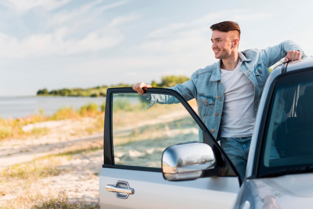 Hombre sonriente de tiro medio posando con coche