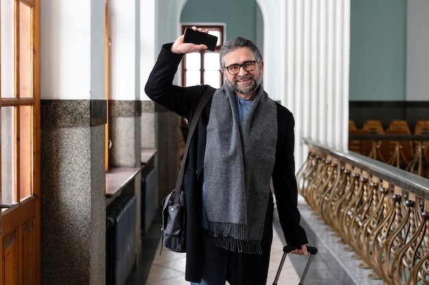 Hombre sonriente de tiro medio que viaja con equipaje