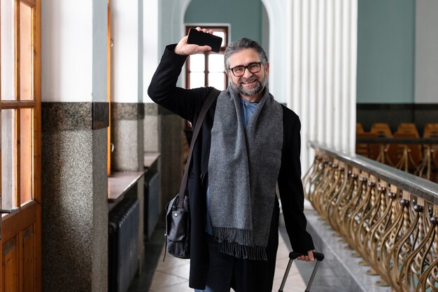 Hombre sonriente de tiro medio que viaja con equipaje