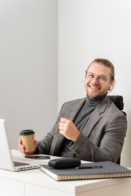 Hombre sonriente de tiro medio sentado en el escritorio