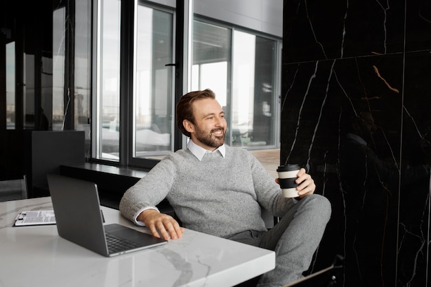 Hombre sonriente de tiro medio sentado en el escritorio