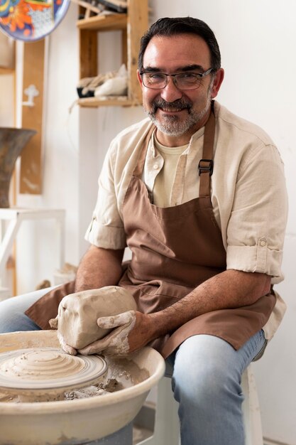 Hombre sonriente de tiro medio sosteniendo arcilla