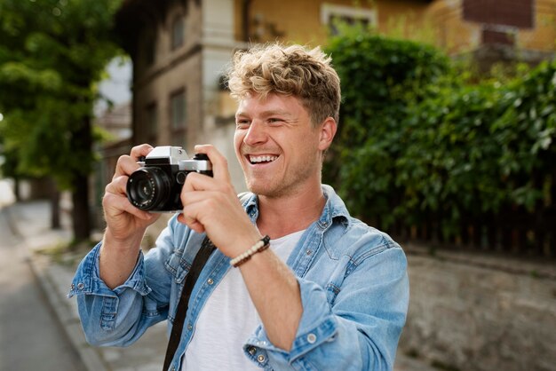 Hombre sonriente de tiro medio sosteniendo la cámara