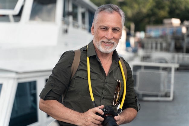 Hombre sonriente de tiro medio sosteniendo la cámara