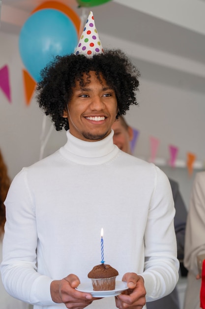 Foto gratuita hombre sonriente de tiro medio sosteniendo cupcake