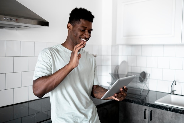 Hombre sonriente de tiro medio con tableta en la cocina