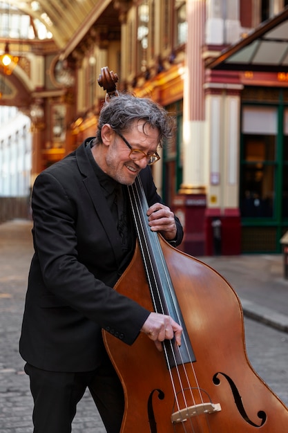 Hombre sonriente de tiro medio tocando el contrabajo