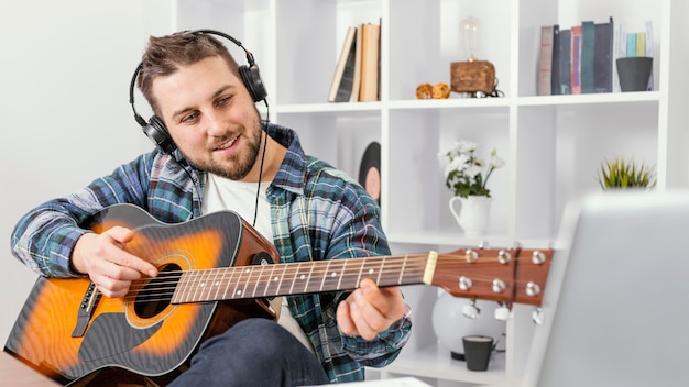Hombre sonriente de tiro medio tocando la guitarra