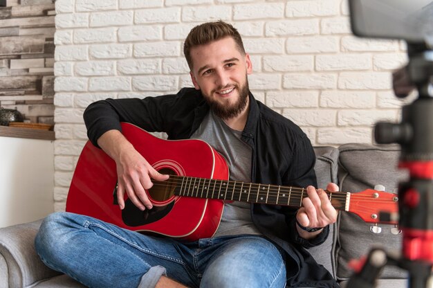 Hombre sonriente de tiro medio tocando la guitarra