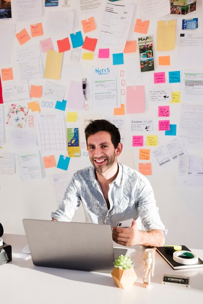 Hombre sonriente de tiro medio trabajando en equipo portátil