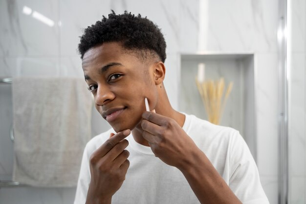 Hombre sonriente de tiro medio usando la herramienta gua sha