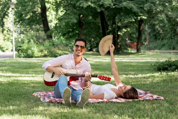 Hombre sonriente tocando la guitarra en el parque