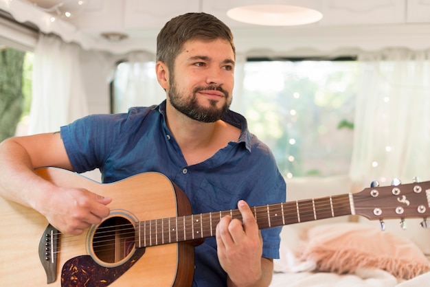 Hombre sonriente tocando la guitarra en su caravana