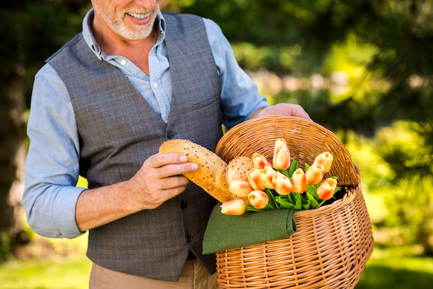 Hombre sonriente tomando una baguette de la cesta de picnic