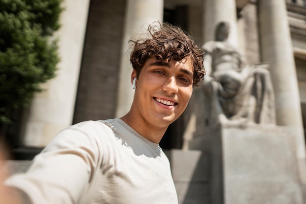 Hombre sonriente tomando selfie al aire libre en ángulo bajo