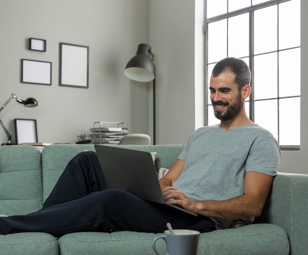 Foto gratuita hombre sonriente trabajando desde casa en portátil