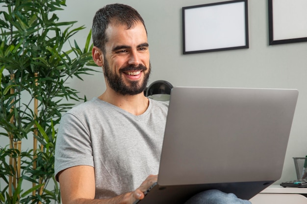 Hombre sonriente trabajando desde casa en portátil