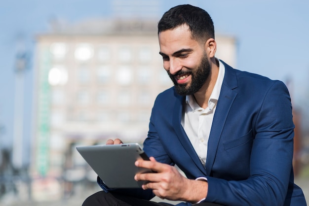 Foto gratuita hombre sonriente trabajando en tableta