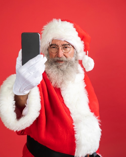 Hombre sonriente en traje de santa con smartphone