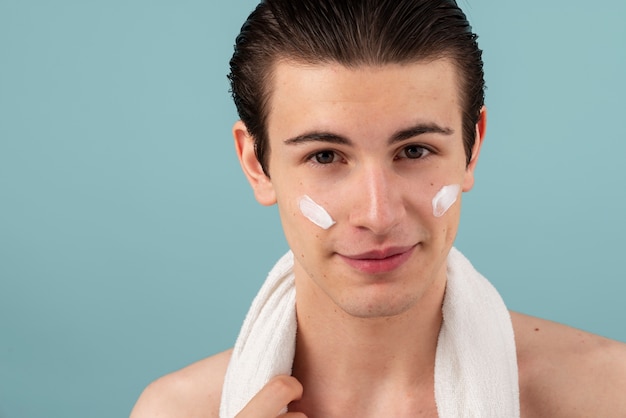 Hombre sonriente con vista frontal de crema facial