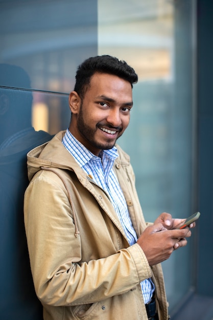 Foto gratuita hombre sonriente con vista lateral del teléfono inteligente