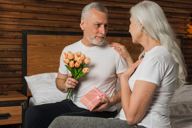 Foto gratuita hombre sorprendente esposa con flores y regalos