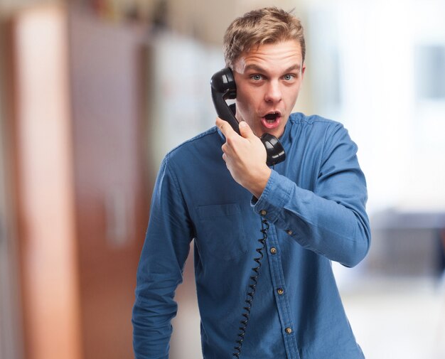 Hombre sorprendido hablando por un teléfono antiguo