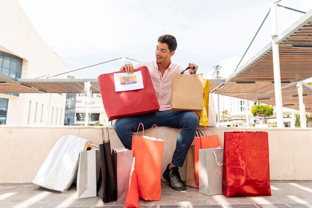 Hombre sorprendido mirando bolsas de compras