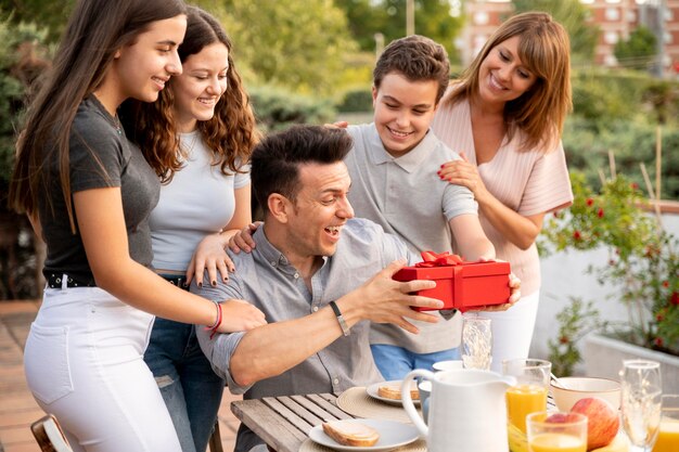 Hombre sorprendido con regalo en reunión familiar