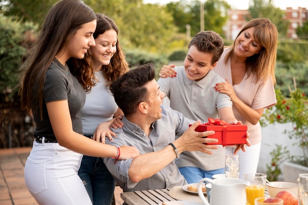 Hombre sorprendido con regalo en reunión familiar