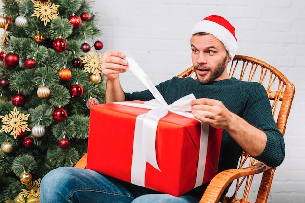 Hombre sorprendido en sombrero de Navidad con caja actual