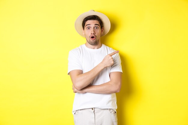 Hombre sorprendido con sombrero de paja apuntando con el dedo hacia la derecha, mostrando un banner promocional, de pie sobre fondo amarillo