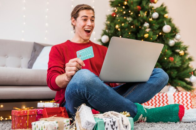 Hombre sorprendido con tarjeta de crédito y portátil